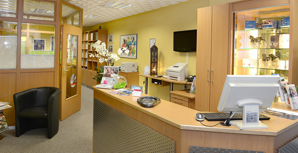 Modernes Reisebüro mit Empfangstresen, Computer, Prospekten und heller Einrichtung.